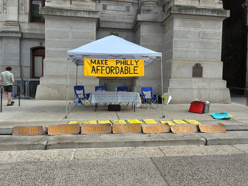 A banner hung up on Sunrise Movement Philadelphia’s tent outside City Hall reads “Make Philly Affordable.”