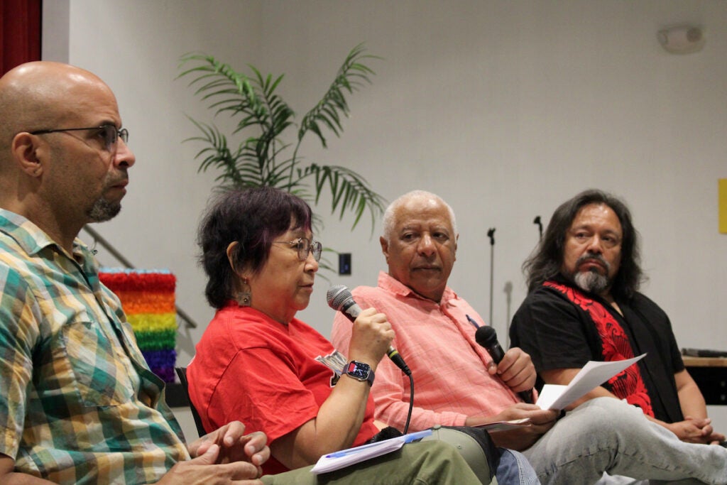 Four people speak into microphones