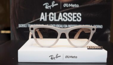 A pair of Ray-Ban and Meta AI glasses is displayed on a white stand with the price tag €329.00. The background features branding for Ray-Ban and Meta with the text "AI GLASSES.