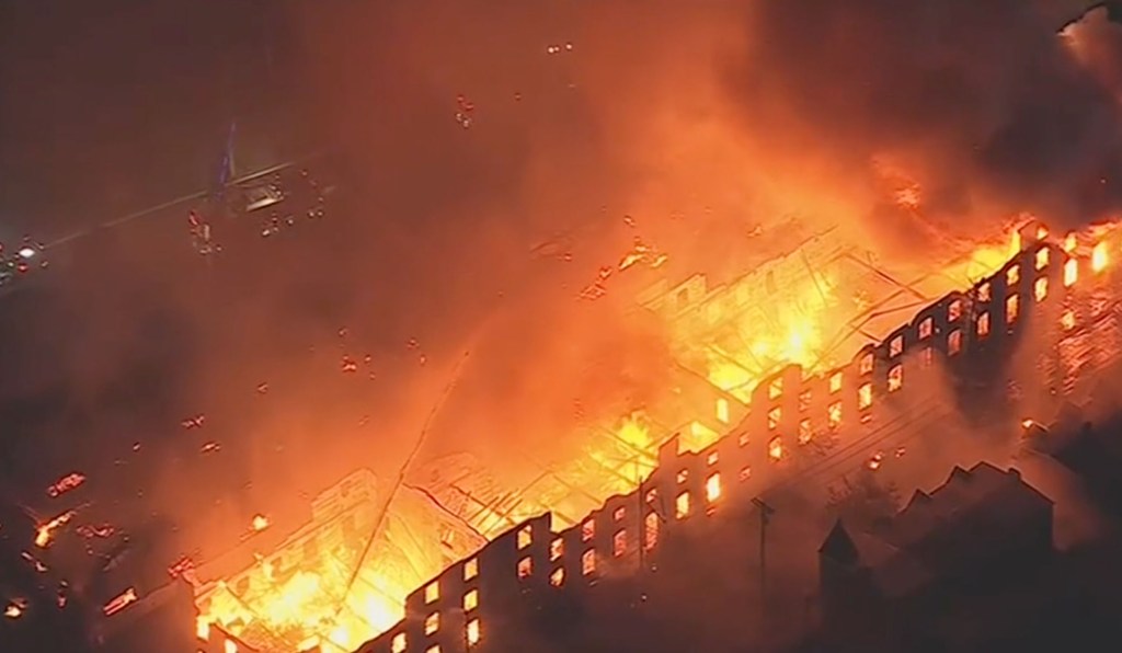 Aerial view of a large commercial building engulfed in a massive six-alarm fire.