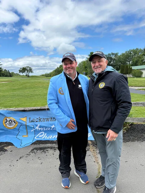 <p>Pat Mitchell, left, dons the blue jacket, emblematic of winning the 2026 Lackawanna County Amateur Championship Golf Tournament held at the end of May at Pine Hills Country Club, Taylor. Mitchell shot a three-under-par 68. At right is Tournament Director Mark Cordelli.</p>
<p>Submitted Photo</p>