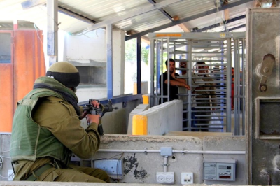 Israeli soldier faces Palestinians waiting at  Huwara checkpoint, Nablus, Wiki Image: 12.06.06