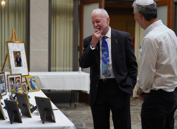 Rabbi Jeffrey Myers of the Tree of Life Congregation, left, reminisces over images presented at his retirement dinner celebration at Rodef Shalom Congregation in Pittsburgh on Friday, July 17, 2026. (AP Photo/Jessie Wardarski)