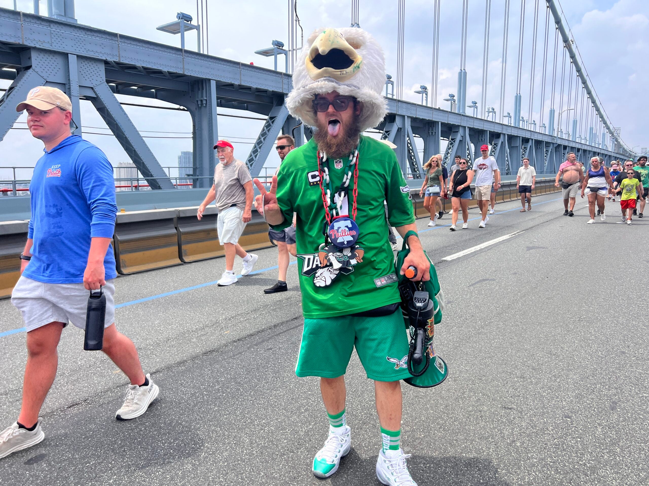 A man dressed in green with a mascot Eagle head propped up on his head. He goes by Philly Swoop Guy 215.