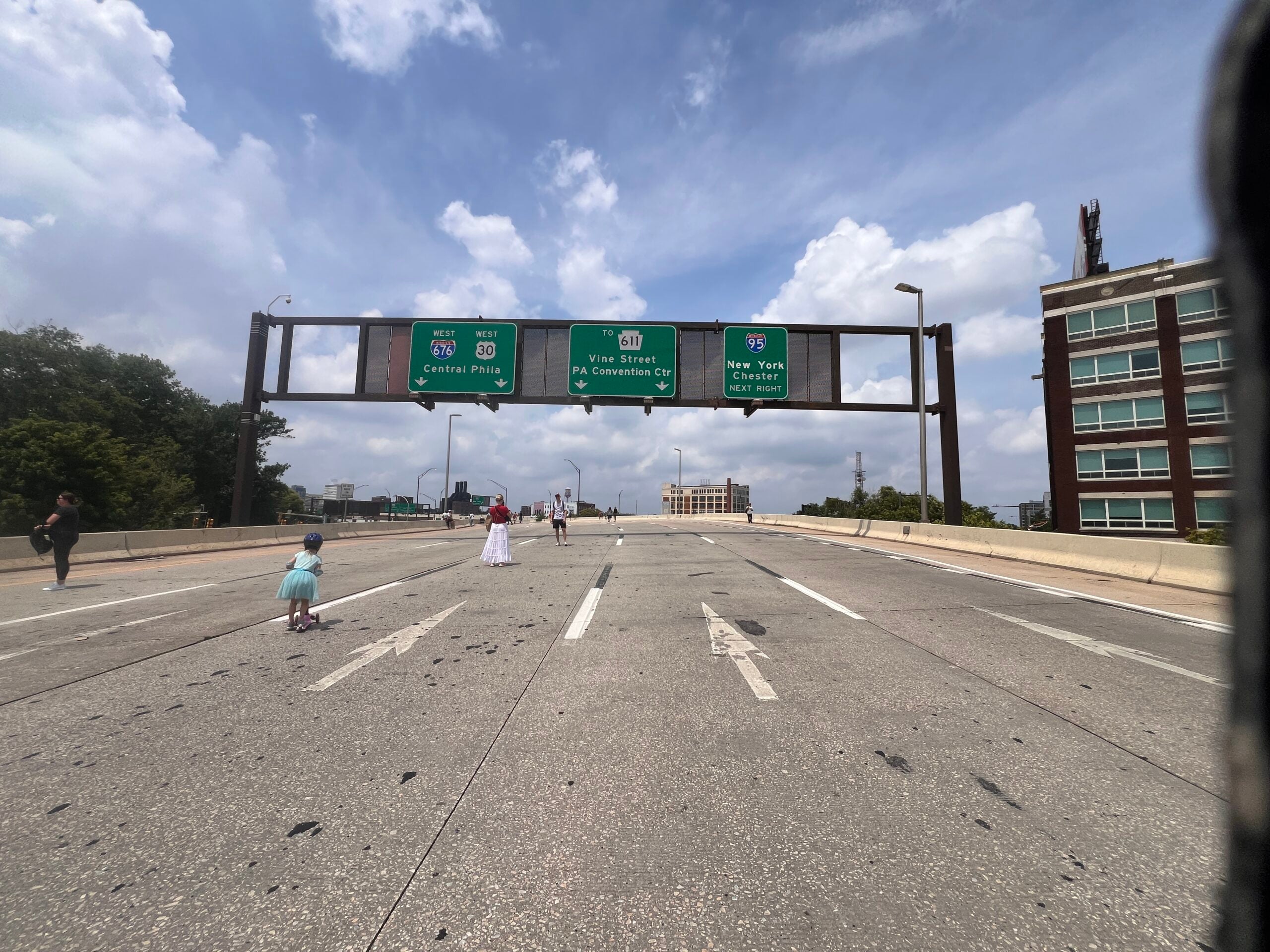 Wide open space where it is usually filled with cars. The base of the Ben Franklin Bridge in Philly was empty toward the Vine Street Expressway. Kristen's daughter Trudy rides her scooter where it's normally full of vehicular traffic.