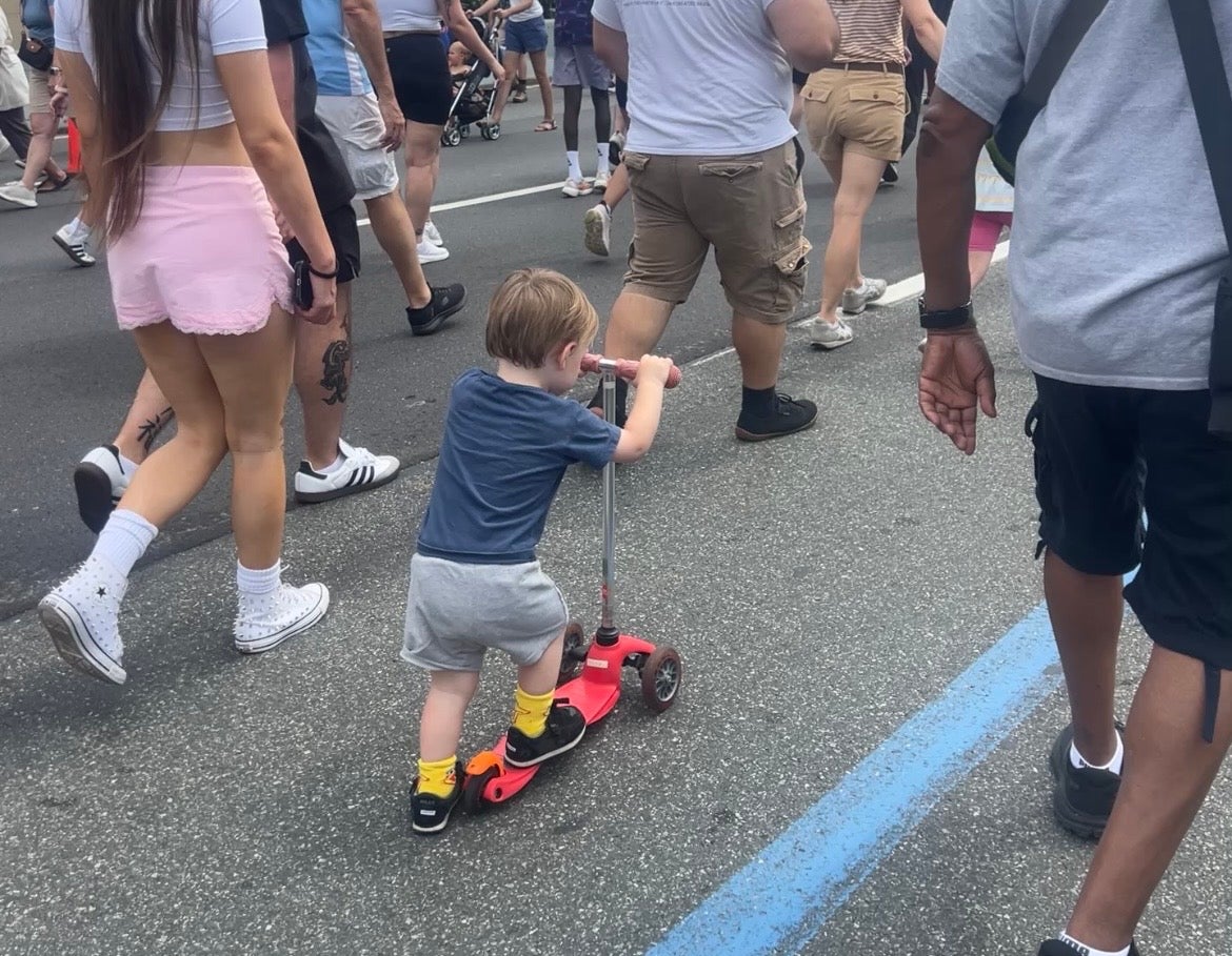 Kristen's 2 year-old son rides a small red scooter among the crowd at the Ben Franklin Bridge 100th Anniversary Celebration.