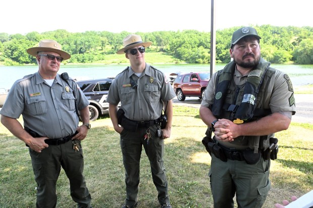 Sgt. Travis Miller, waterways conservation officer with the Pennsylvania Fish and Boat Commission, right, discusses holiday enforcement on Blue Marsh Lake. Joining him during a press event Tuesday were Jeff Piscanio, left, Blue Marsh operations manager, and Jonah Eckert, chief park ranger. (BILL UHRICH/READING EAGLE)