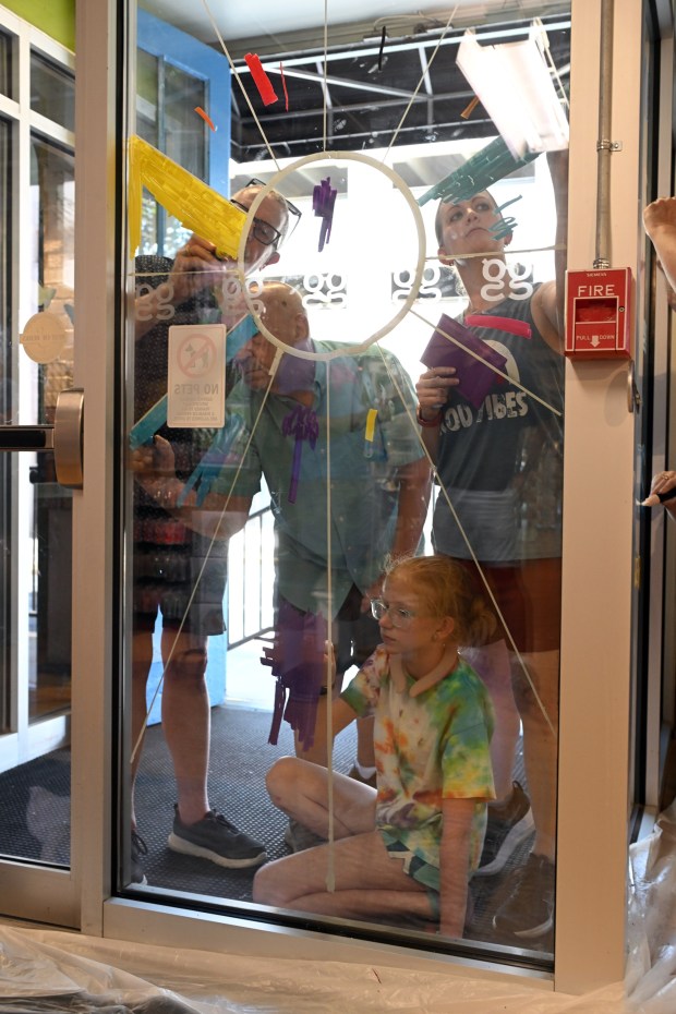 From left, Robert Waffle and Henry Pruski of All Souls Church; and Ashley Myers and her daughter Nina, 12, of Calvary UCC all work on a mural at the GoggleWorks Center for the Arts, 201 Washington St. (BILL UHRICH/READING EAGLE)