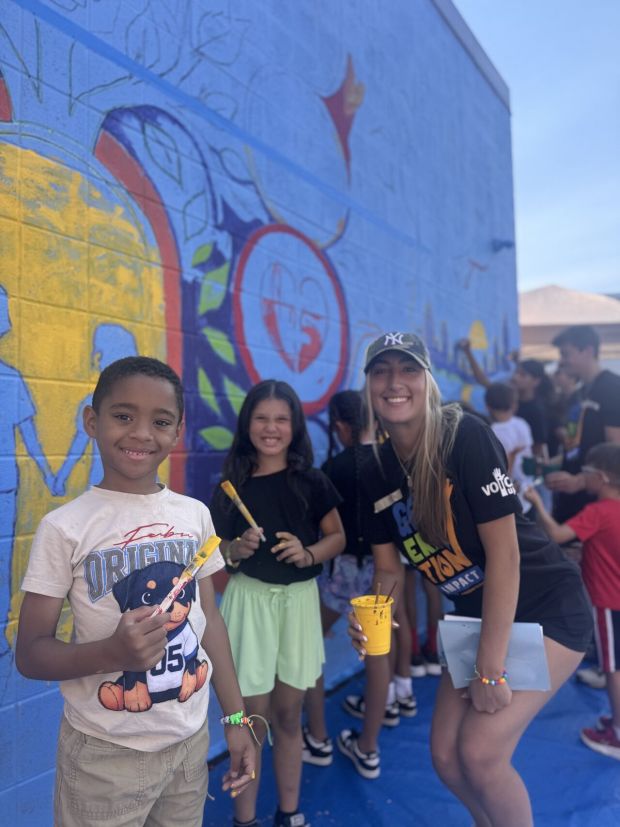 Kayla Franchetti, an East Penn Manufacturing intern who was part of VOiCEup Berks' Generation Impact Initiative, right, works with Olivet Boys & Girls Club members on the mural. (Courtesy of Maddy Fratis, VOiCEup Berks marketing manager)
