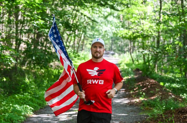 Michael Kravitz runs with the American flag outside of his Spring Brook Twp. residence Thursday, July 9, 2026. (SEAN MCKEAG / STAFF PHOTOGRAPHER)