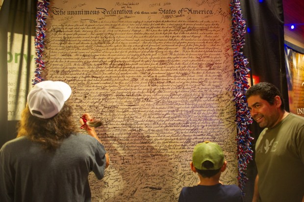 Attendees sign their names on a replica of the Declaration of Independence Friday, July 3, 2026, during the Liberty Ignited celebration marking America's 250th birthday at Coca-Cola Park in Allentown. (Jonathan Broady/Special to The Morning Call)