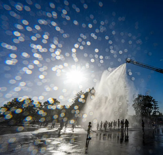 Children and families cool down under the spray Thursday, July 2, 2026, in Coopersburg during a free community cool off event featuring Coopersburg Fire Company's ladder truck spraying water. (April Gamiz/The Morning Call)