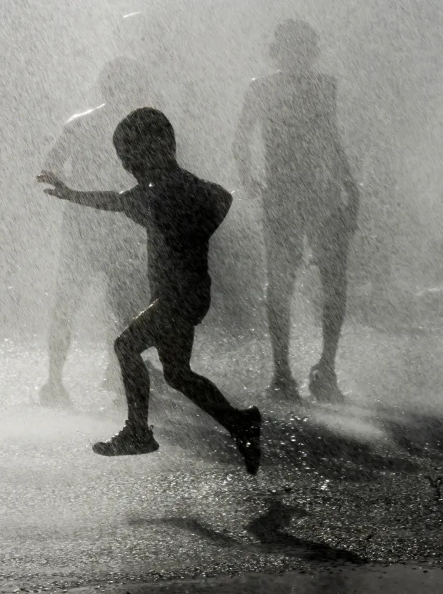 Children and families cool down under the spray Thursday, July 2, 2026, in Coopersburg during a free community cool off event featuring Coopersburg Fire Company's ladder truck spraying water. (April Gamiz/The Morning Call)