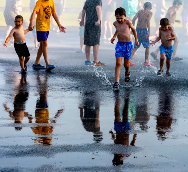 Children and families cool down under the spray Thursday, July 2, 2026, in Coopersburg during a free community cool off event featuring Coopersburg Fire Company's ladder truck spraying water. (April Gamiz/The Morning Call)