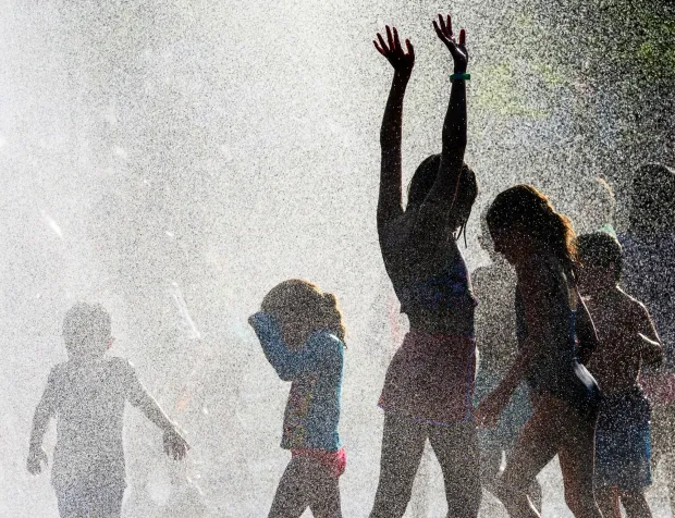 Children and families cool down under the spray Thursday, July 2, 2026, in Coopersburg during a free community cool off event featuring Coopersburg Fire Company's ladder truck spraying water. (April Gamiz/The Morning Call)