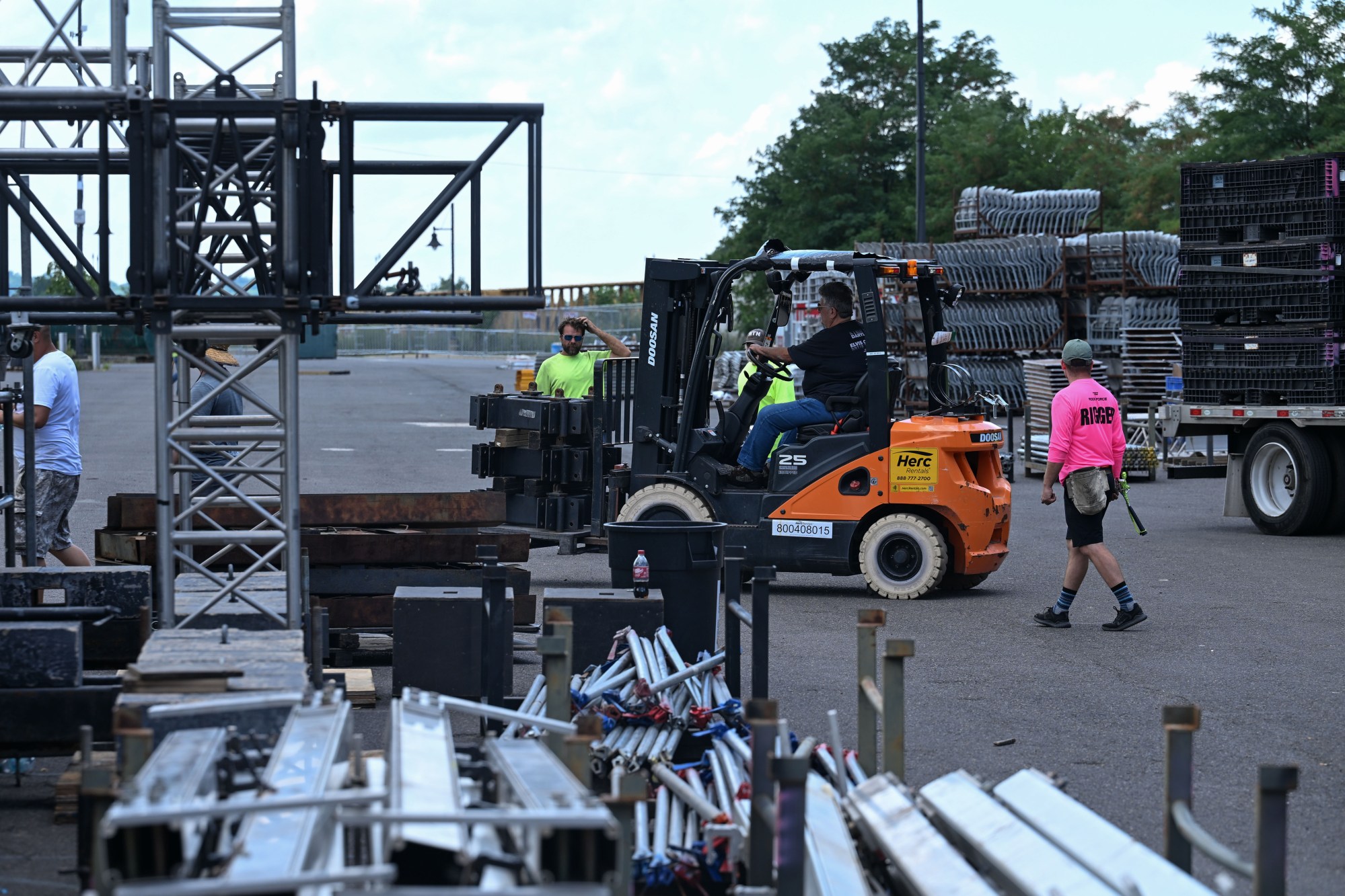 A forklift carries construction materials unloaded from a truck past a group of workers during preparations for MusikFest Wednesday, July 22, 2026, in Bethlehem. The 10-day, free music festival in both North and South Side Bethlehem runs July 31-Aug. 9. (Jon Chiu/The Morning Call)