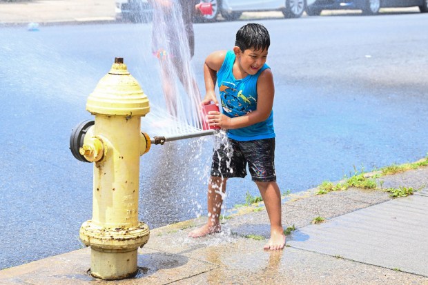 Franco Gonzalez, 6, of Easton uses a toy bucket to try and hold back water from an open fire hydrant Wednesday, July 15, 2026, at the intersection of South 11th and Butler streets in Easton. Eight of the city's hydrants will be open again from noon to 6 p.m. Thursday to combat soaring temperatures. (Jon Chiu/The Morning Call)