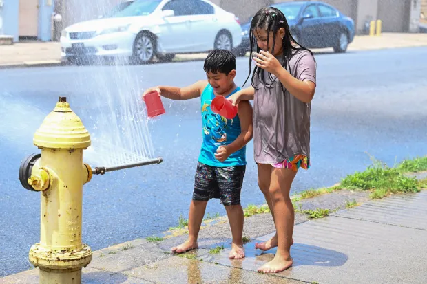 Franco Gonzalez, 6, of Easton plays with his 8-year-old sister, Amy, by an open fire hydrant Wednesday, July 15, 2026, at the intersection of South 11th and Butler streets in Easton. Eight of the city's hydrants will be open again from noon to 6 p.m. Thursday to combat soaring temperatures. (Jon Chiu/The Morning Call)