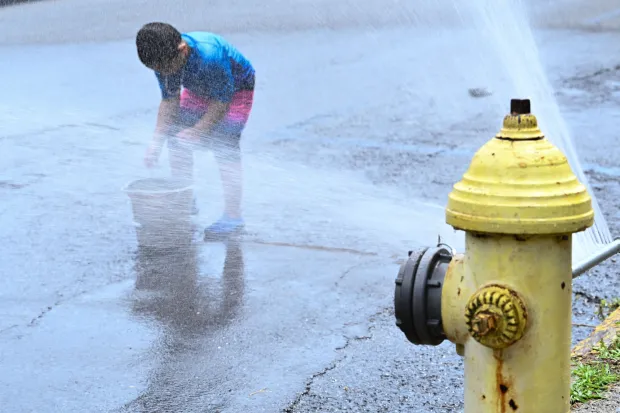 Noah Navarro, 5, of Easton plays with a bucket by an open fire hydrant Wednesday, July 15, 2026, at the intersection of South 11th and Ferry streets in Easton. Eight of the city's hydrants will be open again from noon to 6 p.m. Thursday to combat soaring temperatures. (Jon Chiu/The Morning Call)
