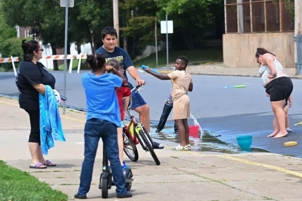 Children play by water flowing from an open fire hydrant Wednesday, July 15, 2026, between Cottingham Stadium and Paxinosa Elementary School in Easton. Eight of the city's hydrants will be open again from noon to 6 p.m. Thursday to combat soaring temperatures. (Jon Chiu/The Morning Call)