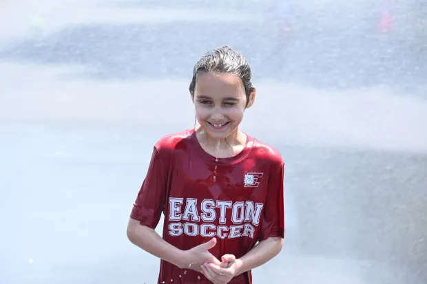 Vanessa Bahrt, 7, of Easton smiles after exiting a stream of water flowing from an open fire hydrant Wednesday, July 15, 2026, between Cottingham Stadium and Paxinosa Elementary School in Easton. Eight of the city's hydrants will be open again from noon to 6 p.m. Thursday to combat soaring temperatures. (Jon Chiu/The Morning Call)