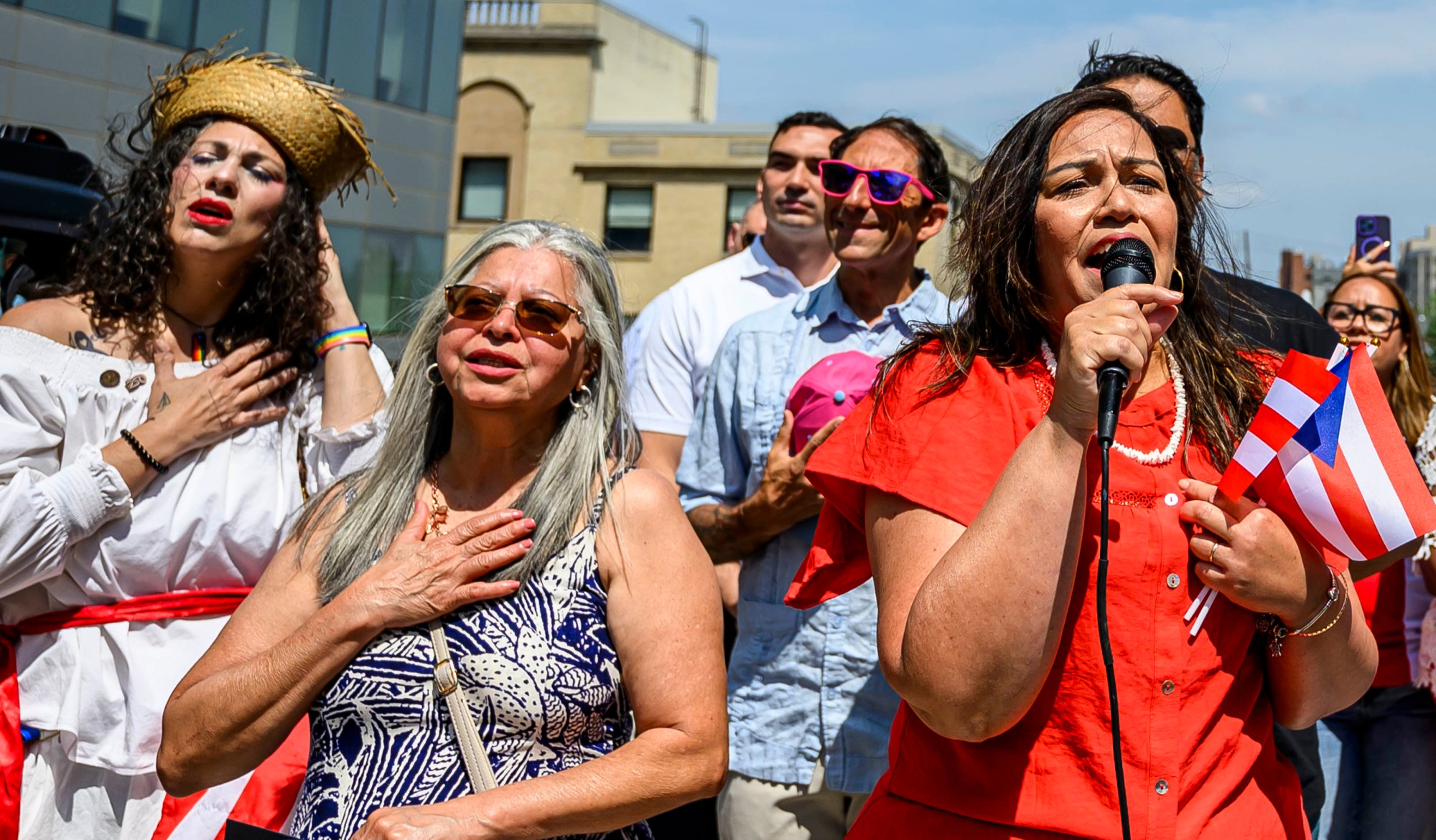 Aracelys Lopez sings the Puerto Rican anthem as she stands next to Flor Vélez, president of Puertorrican Cultural Preservation, during the raising of the Puerto Rican flag before the annual Lehigh Valley Puerto Rican Day Parade and Festival on Sunday, July 19, 2026, in Allentown. (April Gamiz/The Morning Call)