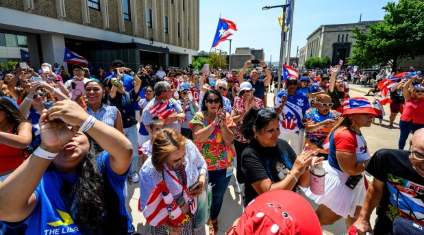 People celebrate raising the raising the Puerto Rican flag before the annual Lehigh Valley Puerto Rican Day Parade on Sunday, July 19, 2026, in Allentown. The day's festivities, sponsored by Puertorrican Cultural Preservation, also included raising the Puerto Rican flag and a festival. (April Gamiz/The Morning Call)