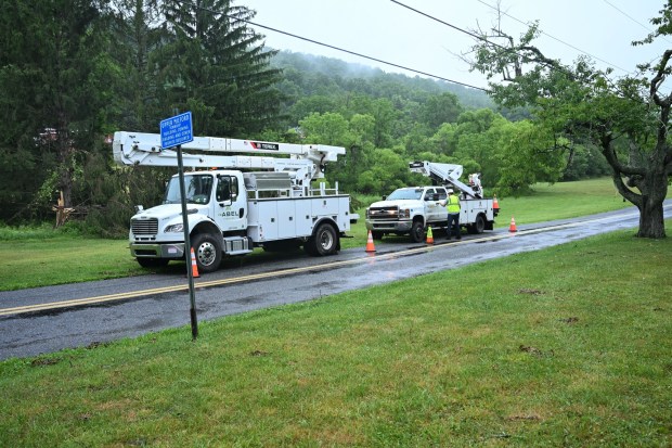Utility vehicles park on the side of the road near Victory Valley Camp to help clear storm damage on Tuesday, July 7, 2026, in Upper Milford Township. Utilities said it could take until Thursday to fully restore power. (Jon Chiu/The Morning Call)