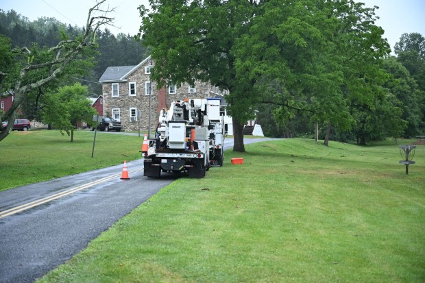 Utility vehicles park on the side of the road near Victory Valley Camp to help clear storm damage on Tuesday, July 7, 2026, in Upper Milford Township. Utilities said it could take until Thursday to fully restore power. (Jon Chiu/The Morning Call)