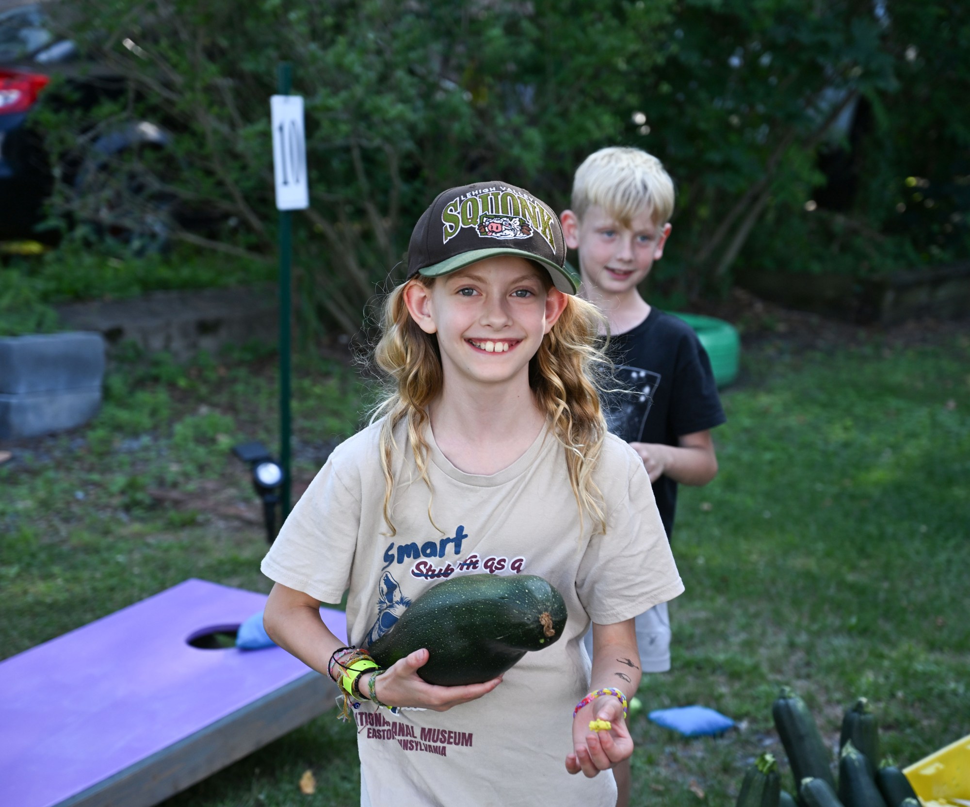 Ellie Nees, 10, and Henry Nees 8, of Easton walk with zucchinis they will make into cars during the 20th Annual Zucchini 500 on Thursday, July 23, 2026 at the 10th & Pine street community garden in Easton. According to West Ward Community Initiative manager Jacob Behler, events like the 'Zuke 500' are meant to help foster new community connections and help people have affordable and local access to healthy produce. (Jon Chiu/The Morning Call)