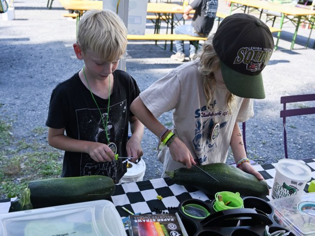 Ellie, 10, and Henry Nees, 8, of Easton work on their zucchini cars during the 20th Annual Zucchini 500 Thursday, July 23, 2026 at the 10th & Pine street community garden in Easton. According to West Ward Community Initiative manager Jacob Behler, events like the 'Zuke 500' are meant to help foster new community connections and help people have affordable and local access to healthy produce. (Jon Chiu/The Morning Call)