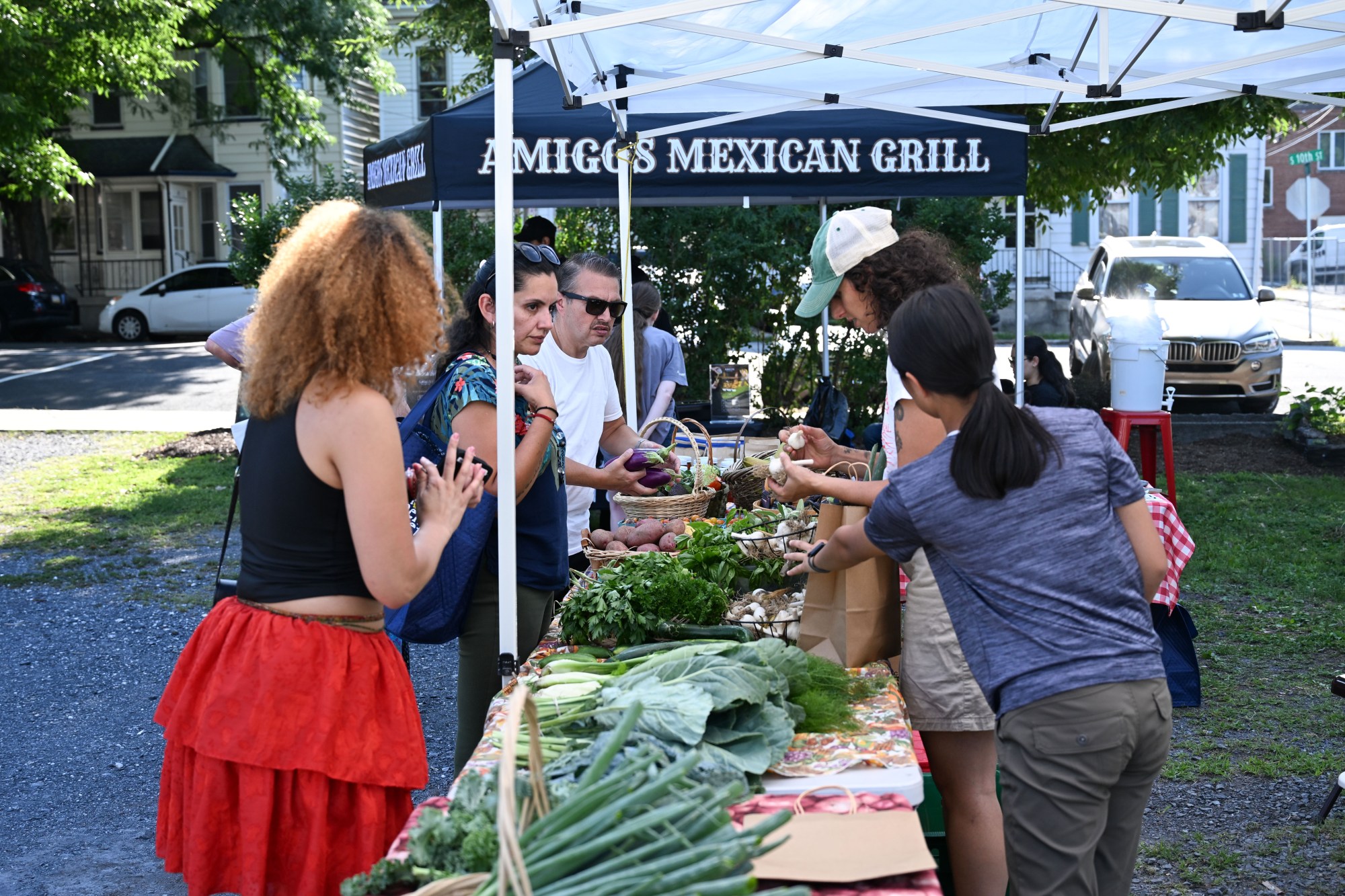People inspect and purchase produce from Easton Garden Works during the 20th Annual Zucchini 500 on Thursday, July 23, 2026 at the 10th & Pine street community garden in Easton. According to West Ward Community Initiative manager Jacob Behler, events like the 'Zuke 500' are meant to help foster new community connections and help people have affordable and local access to healthy produce. (Jon Chiu/The Morning Call)