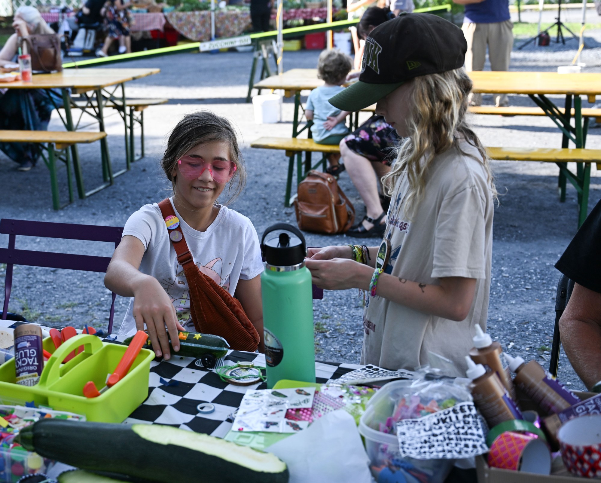 Annika Schwartz, 10, shows her zucchini car to Ellie Nees, 10, during the 20th Annual Zucchini 500 on Thursday, July 23, 2026 at the 10th & Pine street community garden in Easton. According to West Ward Community Initiative manager Jacob Behler, events like the 'Zuke 500' are meant to help foster new community connections and help people have affordable and local access to healthy produce. (Jon Chiu/The Morning Call)
