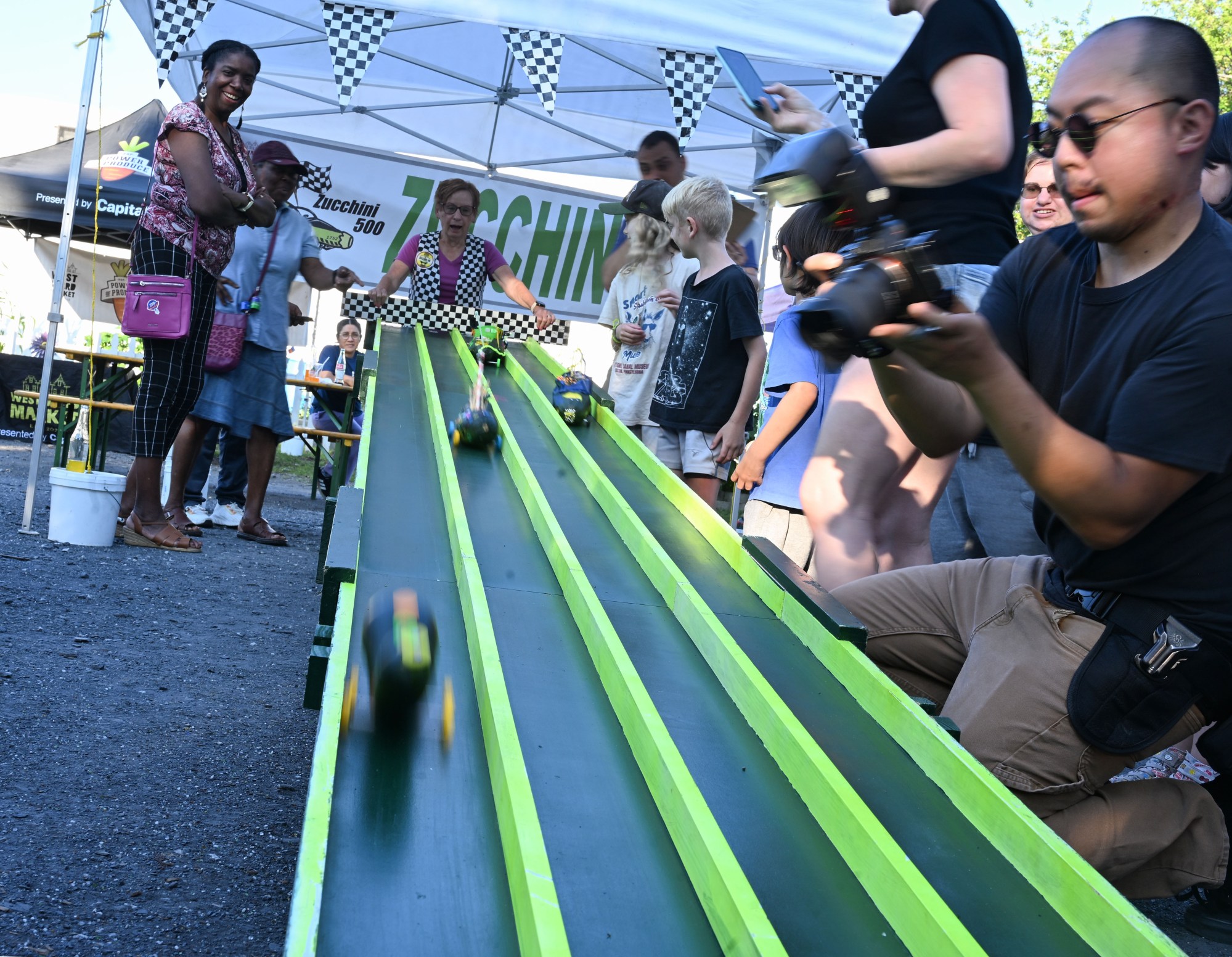 Zucchini cars race down the track during the 20th Annual Zucchini 500 on Thursday, July 23, 2026 at the 10th & Pine street community garden in Easton. According to West Ward Community Initiative manager Jacob Behler, events like the 'Zuke 500' are meant to help foster new community connections and help people have affordable and local access to healthy produce. (Jon Chiu/The Morning Call)