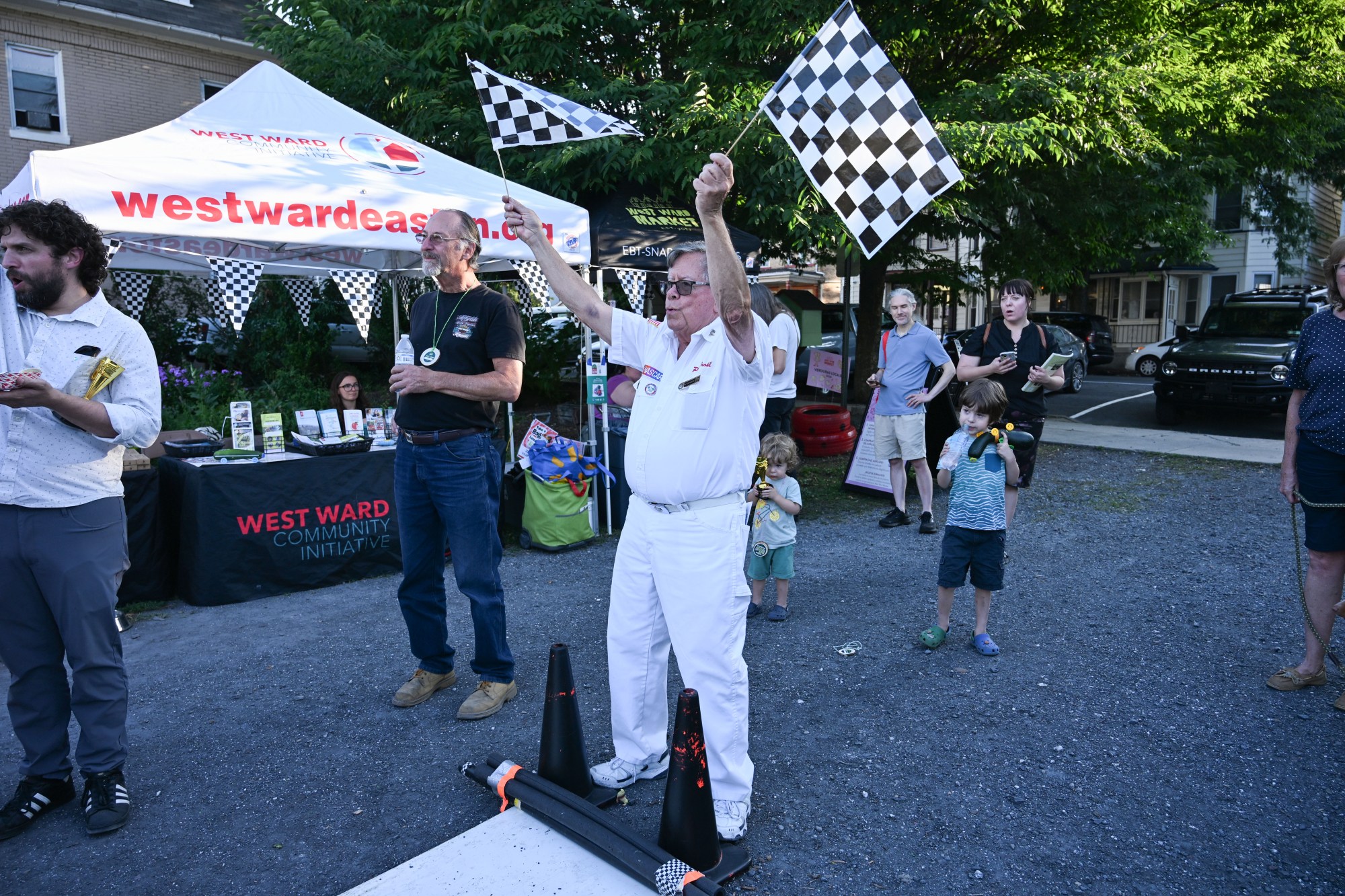NASCAR official Peter Brohl waves racing flags during the 20th Annual Zucchini 500 on Thursday, July 23, 2026 at the 10th & Pine street community garden in Easton. According to West Ward Community Initiative manager Jacob Behler, events like the 'Zuke 500' are meant to help foster new community connections and help people have affordable and local access to healthy produce. (Jon Chiu/The Morning Call)
