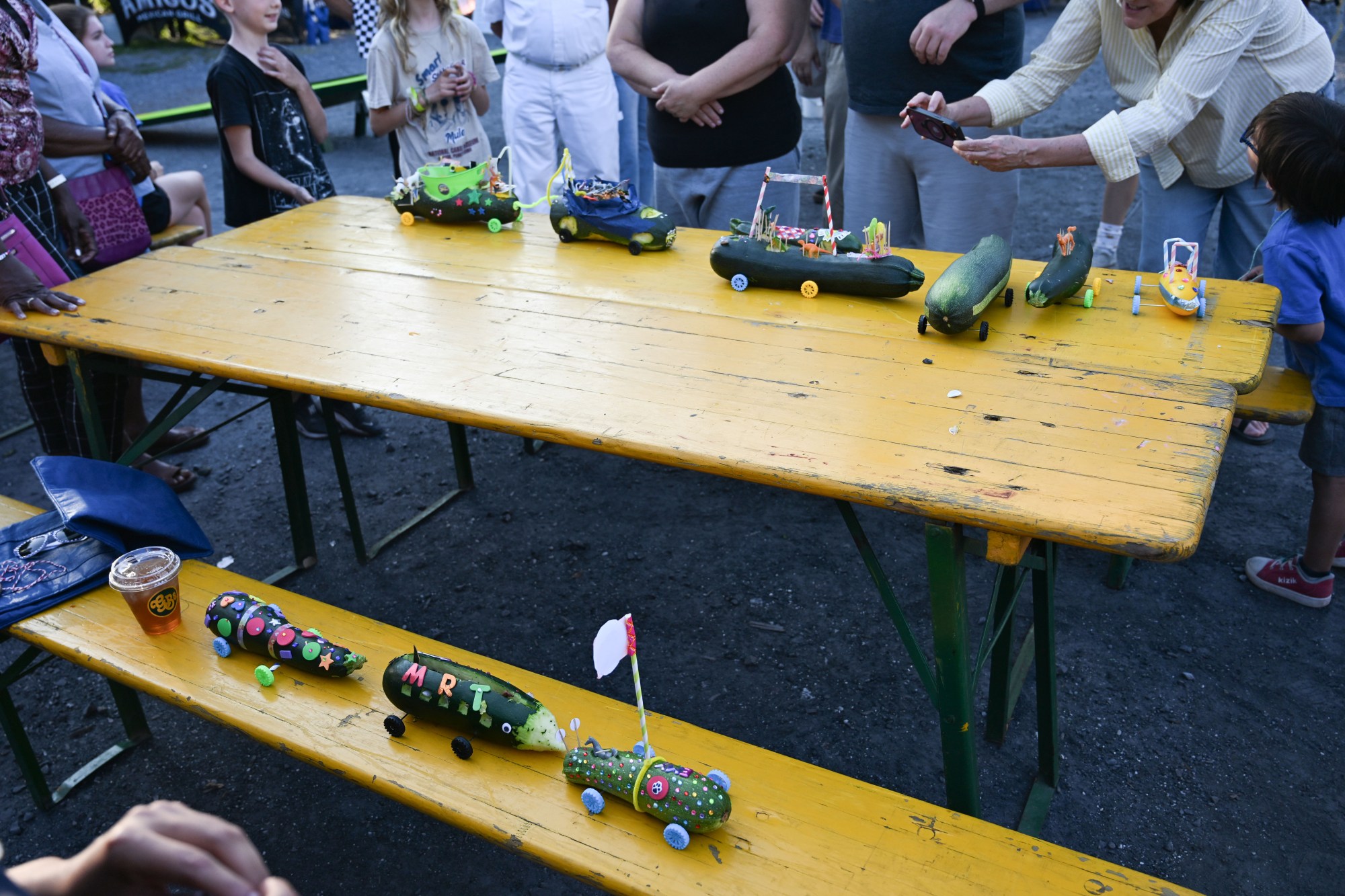 Zucchini cars are displayed on a table during judging for the award for most creative car during the 20th Annual Zucchini 500 on Thursday, July 23, 2026 at the 10th & Pine street community garden in Easton. According to West Ward Community Initiative manager Jacob Behler, events like the 'Zuke 500' are meant to help foster new community connections and help people have affordable and local access to healthy produce. (Jon Chiu/The Morning Call)