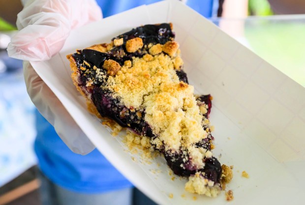 Volunteer Esmeralda Herrera, 15, of Allentown adds slices of blueberry pie to a display case on Saturday, July 18, 2026,  during Bethlehem Blueberry Festival, organized by Historic Bethlehem Museums & Sites at Burnside Plantation.  The festival offers Colonial demonstrations, activities, vendor tents, blueberry-themed foods and live music. (April Gamiz/The Morning Call)