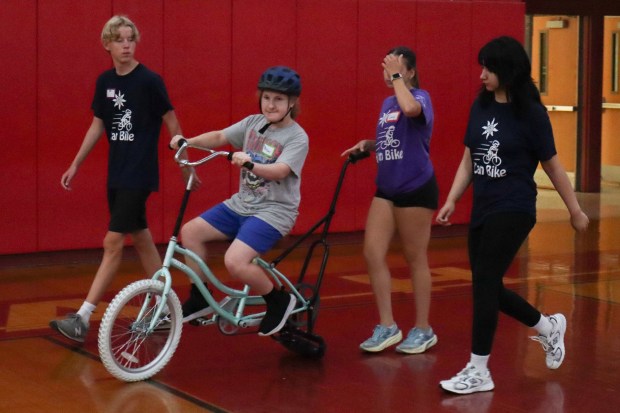 Anna Bella Cunerd of Bethlehem, 13, rides a training bicycle with help from iCanBike volunteers Wednesday, July 29, 2026, at Easton Area High School in Palmer Township. iCanBike will remain at the high school to teach individuals with various disabilities how to ride both training and conventional bicycles until Friday. (Jon Chiu/The Morning Call)
