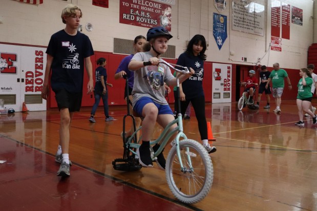 Anna Bella Cunerd of Bethlehem, 13, rides a training bicycle with help from iCanBike volunteers Wednesday, July 29, 2026, at Easton Area High School in Palmer Township. iCanBike will remain at the high school to teach individuals with various disabilities how to ride both training and conventional bicycles until Friday. (Jon Chiu/The Morning Call)