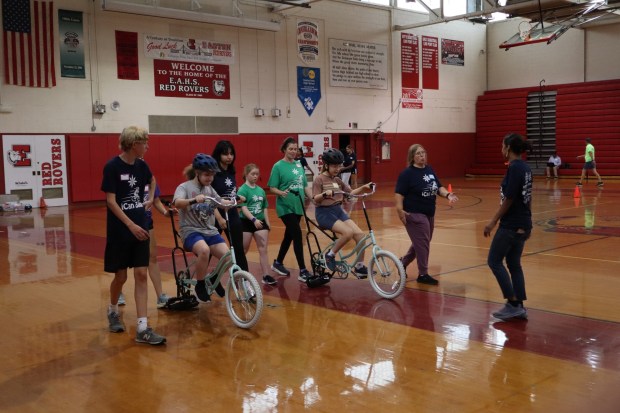 Anna Bella Cunerd of Bethlehem, 13, and Jude Jennings of Bethlehem, 8, ride training bicycles with help from iCanBike volunteers Wednesday, July 29, 2026, at Easton Area High School in Palmer Township. iCanBike will remain at the high school to teach individuals with various disabilities how to ride both training and conventional bicycles until Friday. (Jon Chiu/The Morning Call)
