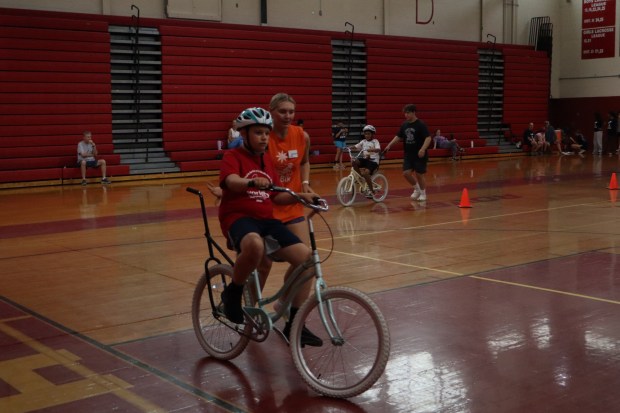 Alex Lewullis of Allentown, 12, rides a bicycle with help from iCanBike floor supervisor Makayla Burngardt Wednesday, July 29, 2026, at Easton Area High School in Palmer Township. iCanBike will remain at the high school to teach individuals with various disabilities how to ride both training and conventional bicycles until Friday. (Jon Chiu/The Morning Call)