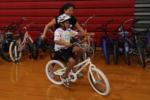iCanBike volunteer Mandy Wang helps Jax O'Leary of Easton, 8, ride a bicycle Wednesday, July 29, 2026, at Easton Area High School in Palmer Township. iCanBike will remain at the high school to teach individuals with various disabilities how to ride both training and conventional bicycles until Friday. (Jon Chiu/The Morning Call)