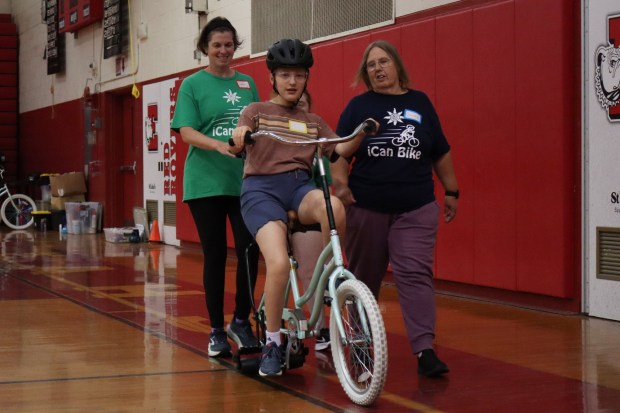 Jude Jennings of Bethlehem, 8, rides a training bicycle with help from iCanBike volunteers Wednesday, July 29, 2026, at Easton Area High School in Palmer Township. iCanBike will remain at the high school to teach individuals with various disabilities how to ride both training and conventional bicycles until Friday. (Jon Chiu/The Morning Call)