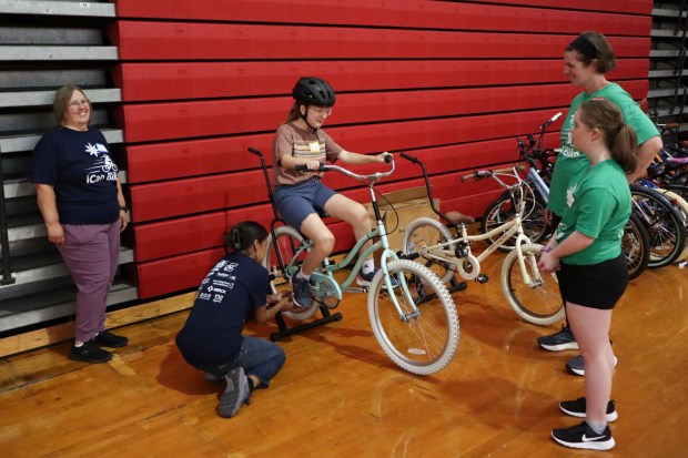 Volunteers from iCanBike help Jude Jennings of Bethlehem, 8, strengthen her legs to ride a bicycle Wednesday, July 29, 2026, at Easton Area High School in Palmer Township. iCanBike will remain at the high school to teach individuals with various disabilities how to ride both training and conventional bicycles until Friday. (Jon Chiu/The Morning Call)
