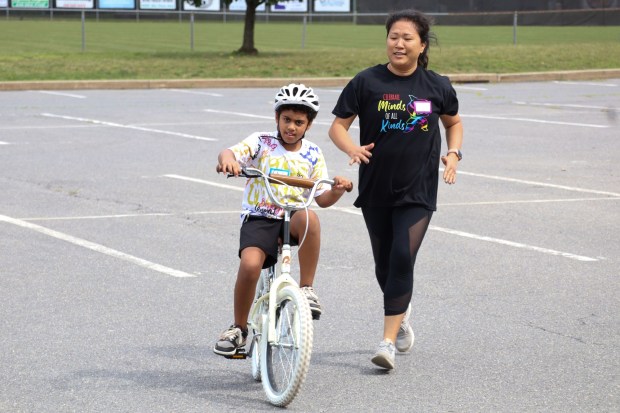 iCanBike volunteer Mandy Wang helps Jax O'Leary of Easton, 8, ride a bicycle Wednesday, July 29, 2026, at Easton Area High School in Palmer Township. iCanBike will remain at the high school to teach individuals with various disabilities how to ride both training and conventional bicycles until Friday. (Jon Chiu/The Morning Call)