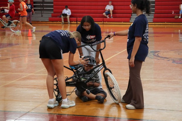 Volunteers from iCanBike encourage Xander Hartner of Bethlehem, 17, to get back on a training bike after falling from it Wednesday, July 29, 2026, at Easton Area High School in Palmer Township. iCanBike will remain at the high school to teach individuals with various disabilities how to ride both training and conventional bicycles until Friday. (Jon Chiu/The Morning Call)