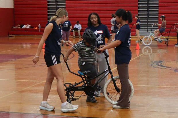 Xander Hartner of Bethlehem, 17, gets back on a training bicycle with help from iCanBike volunteers after falling from it Wednesday, July 29, 2026, at Easton Area High School in Palmer Township. iCanBike will remain at the high school to teach individuals with various disabilities how to ride both training and conventional bicycles until Friday. (Jon Chiu/The Morning Call)