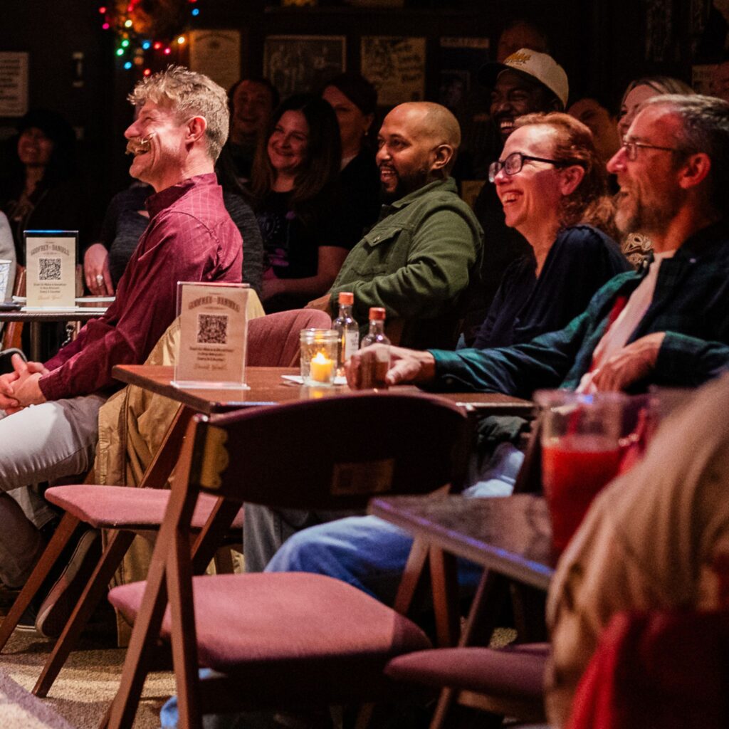 Audience members laughing at a comedy set