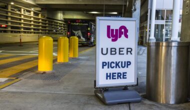 A sign indicating Uber and Lyft pickup locations at a parking area, with yellow bollards nearby.