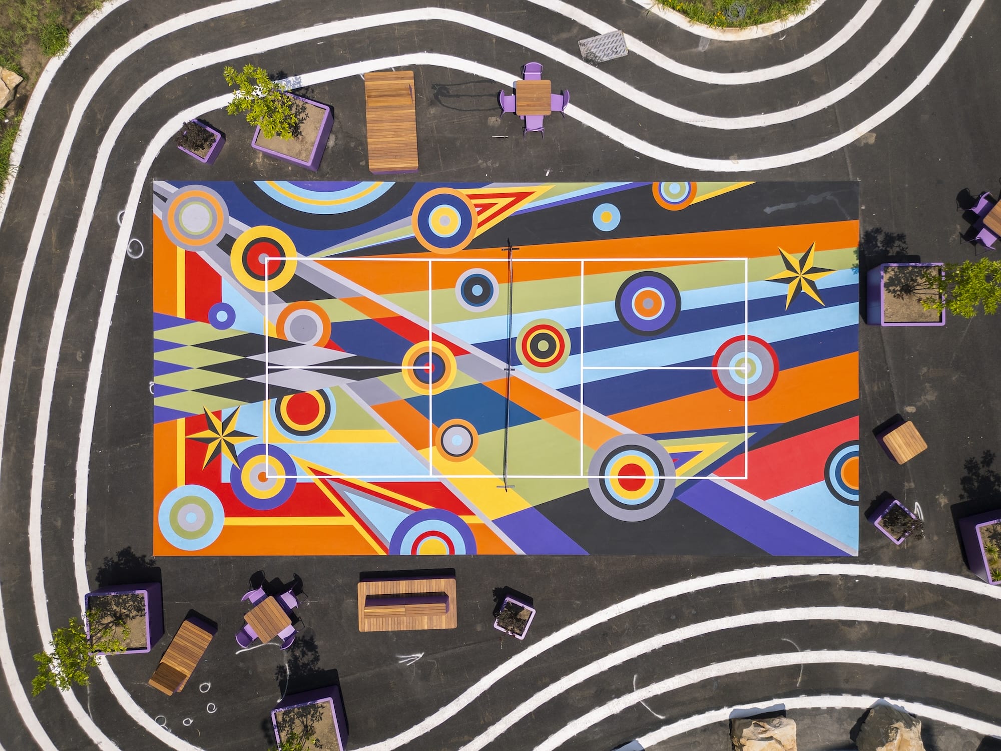 a drone view of one of three pickleball courts in downtown Pittsburgh painted with bright geometric, abstract murals